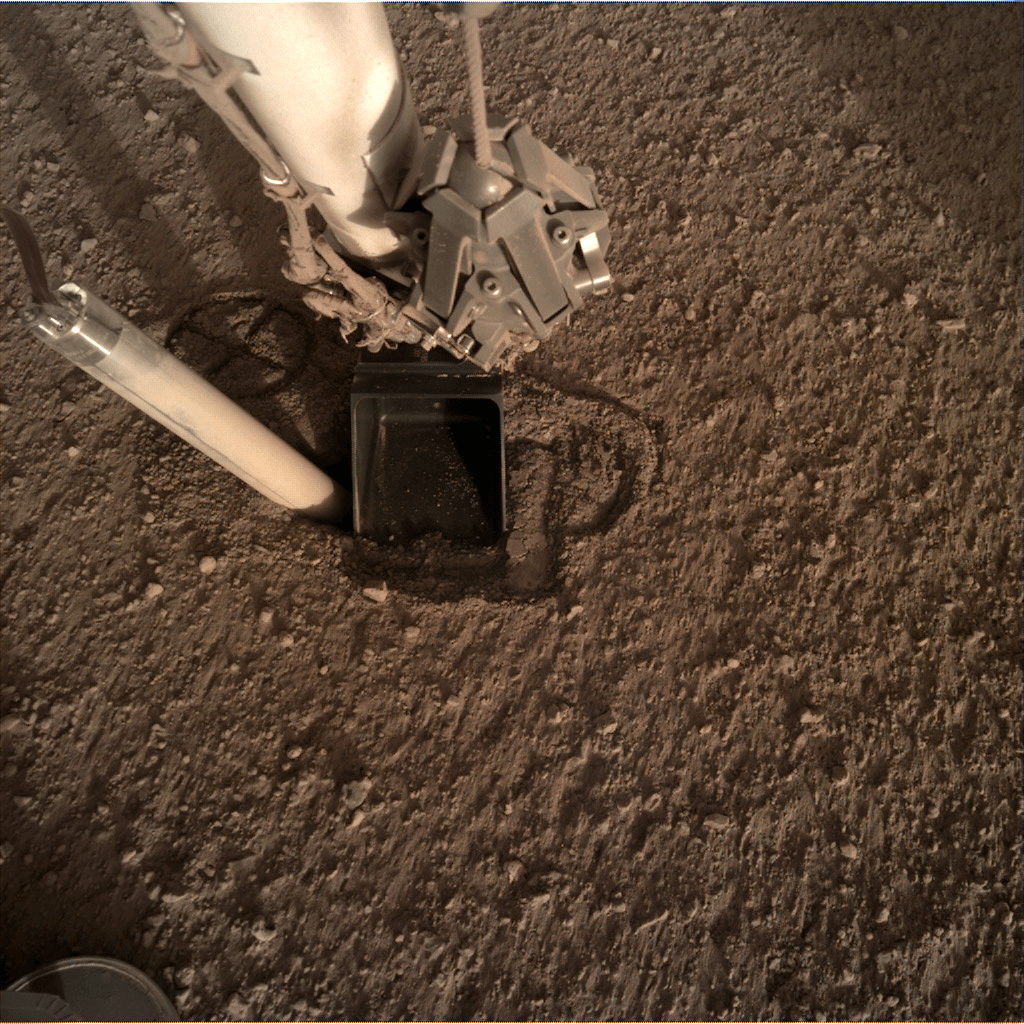 穴が土に埋められたことで地上に半ば飛び出してしまったモール（画像左の筒状の装置）。ロボットアームは摩擦を強めるために用いられた（Credit: NASA/JPL-Caltech）