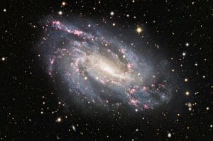 幾つもの赤い領域があちこちで輝く花火のような渦巻銀河