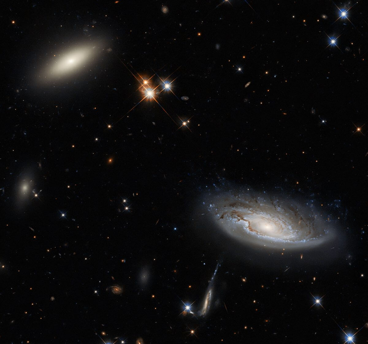 ハッブル宇宙望遠鏡が撮影、ペルセウス座銀河団の一角で輝く渦巻銀河とレンズ状銀河