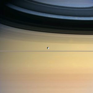 土星本体を背景に細く写る土星の環、および土星の衛星ディオネ（Credit: NASA/JPL/Space Science Institute）
