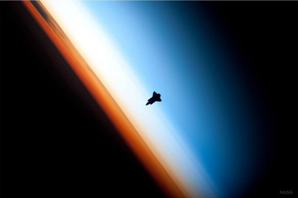 2010年に国際宇宙ステーションから撮影された画像。層状の大気とスペースシャトル「エンデバー」が写っています（Credit: NASA, Expedition 22 Crew）