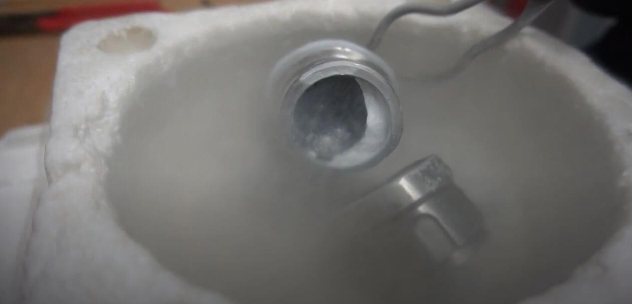 【▲ 図1: 写真中央、金属の容器の中にある白い固体が中密度非晶質氷である。液体窒素中で冷やされたボールミル容器の中で合成された。 (Image Credit: University College London) 】