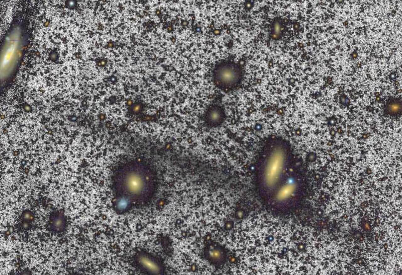 【▲図1: 左上から右下にかけて濃い灰色でハイライトされた細長い恒星の分布が、今回発見された巨大かみのけ座ストリーム。 (Image Credit: ERON, WHT & Román et al.) 】