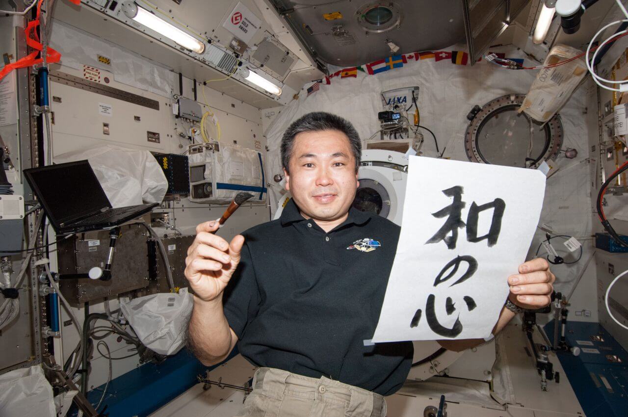 【▲ 国際宇宙ステーション（ISS）で書いた書き初めを手にする長期滞在中の若田光一さん。2014年1月1日撮影（Credit: JAXA/NASA）】