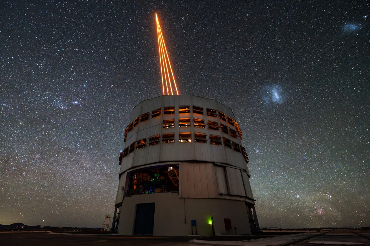 補償光学用のレーザービームを照射するパラナル天文台のVLT=超大型望遠鏡(Credit: ESO)