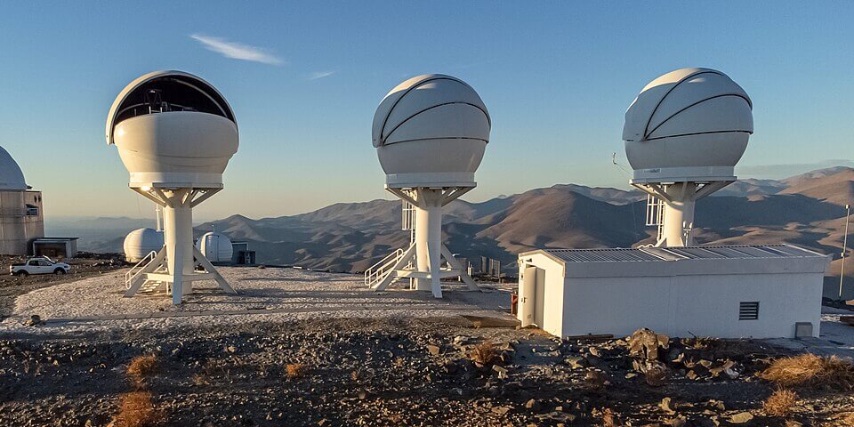 2023年に完成し科学観測を開始したBlackGEM望遠鏡3台。チリのESOラ・シヤ天文台に設置されており、高い台座の上に球形の白いドームが乗った特徴的な姿で並んでいる（Credit: Credit: ESO/Zdeněk Bardon (bardon.cz), CC BY 4.0）