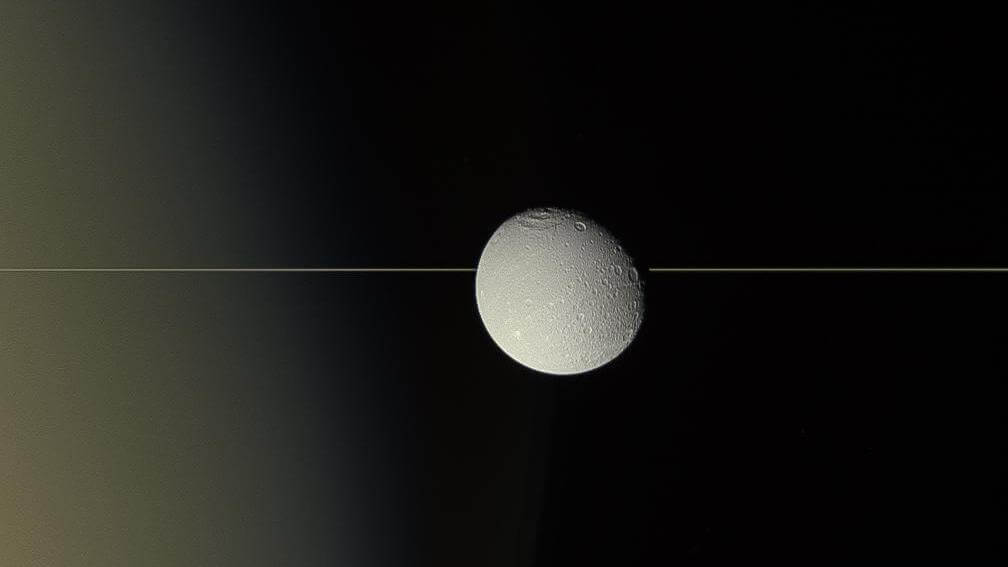 衛星ディオネの背後を横切る“一本線” その正体は土星の環