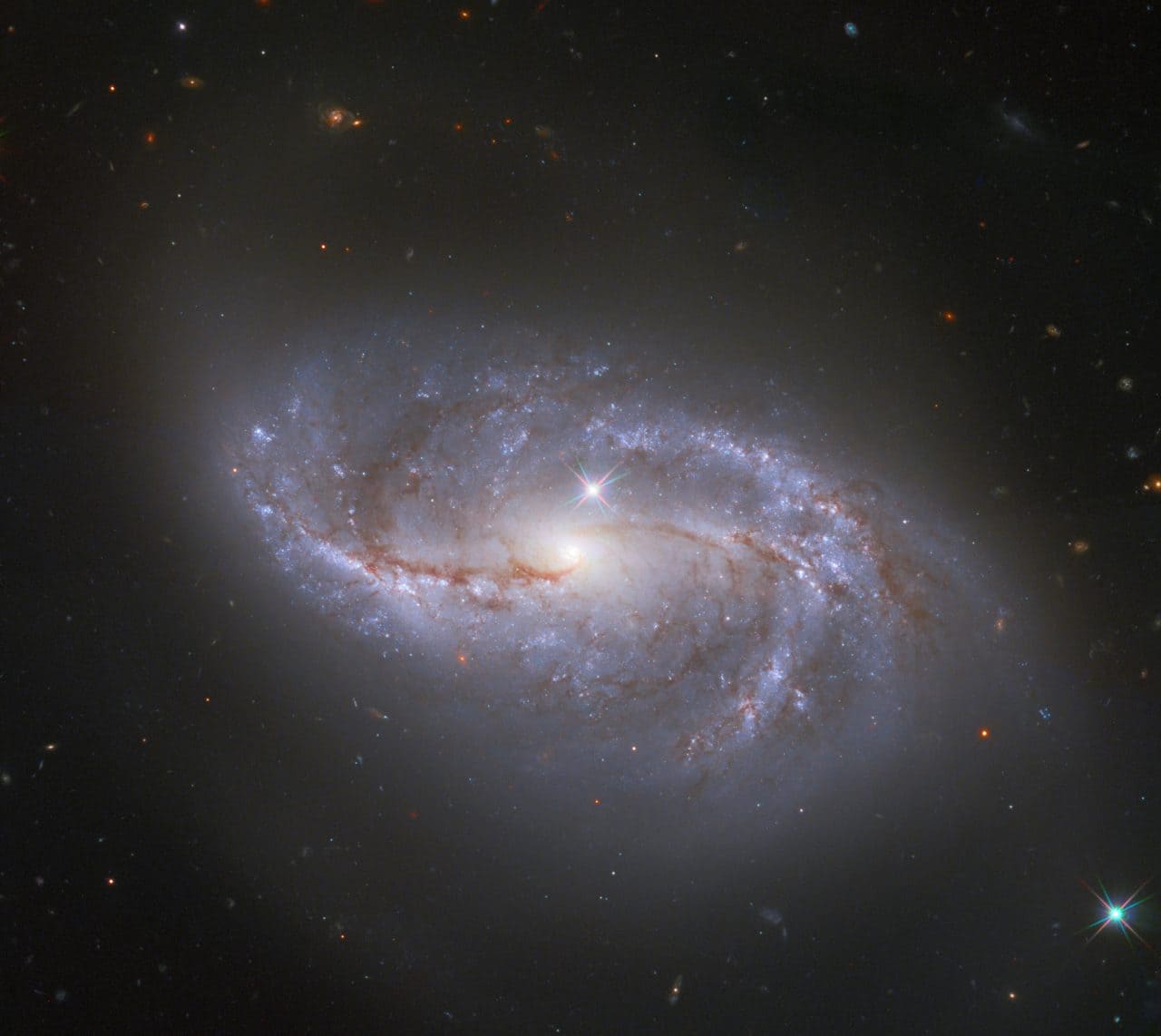 重なり合う星と銀河の輝き ハッブル宇宙望遠鏡が観測した棒渦巻銀河「NGC 2608」